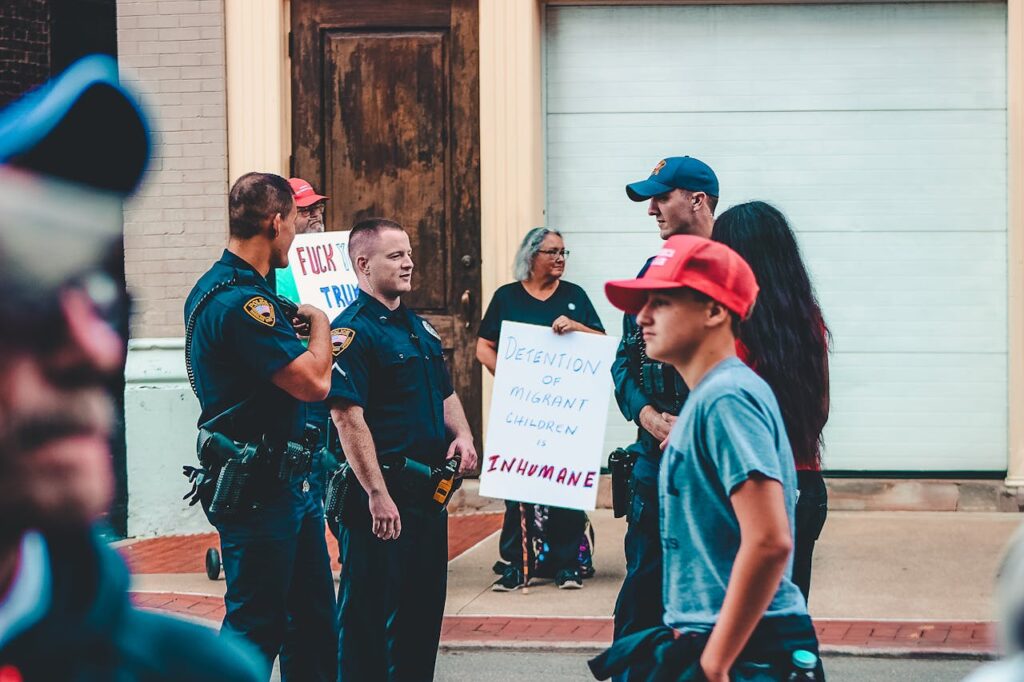 Street protest in Wheeling, WV highlighting immigration issues with signs and police presence.