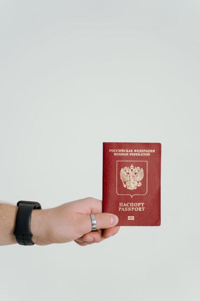 Close-up of a hand holding a Russian Federation passport on a white background.